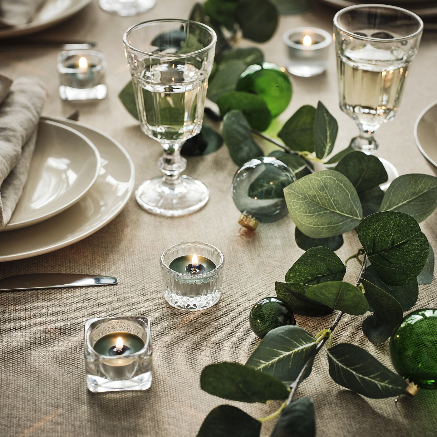 Kolekcja zielonych świec tea-light VINTERFINT w aluminiowych filiżankach, starannie ułożonych.